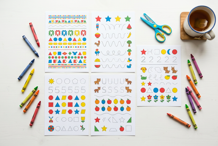Printed toddler activity pages with crayons on a white table